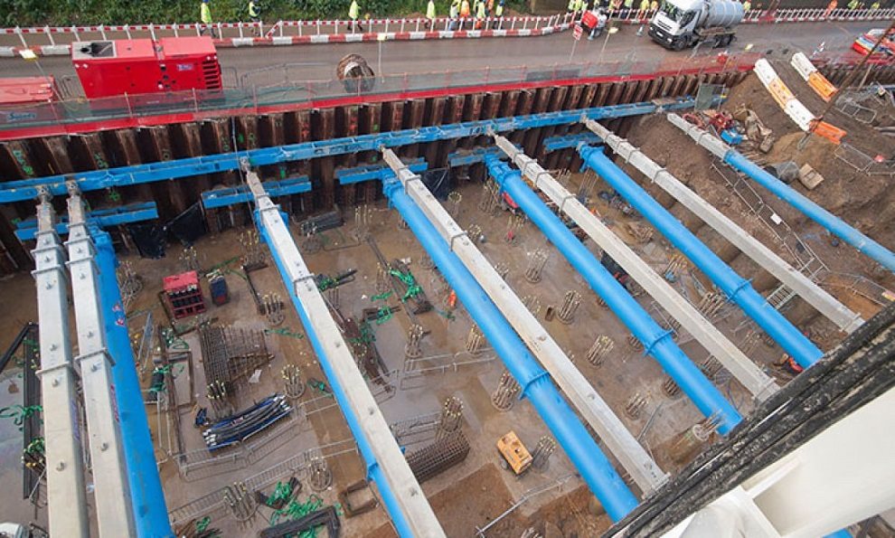 Groundworks support equipment on a large four sided excavation showing sheet pile wall, ground works and edge protection for a basement construction